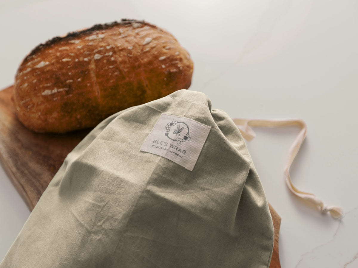 Bakery Lane Bread Bag with a Bee's Wrap label next to a loaf of bread on a wooden board.